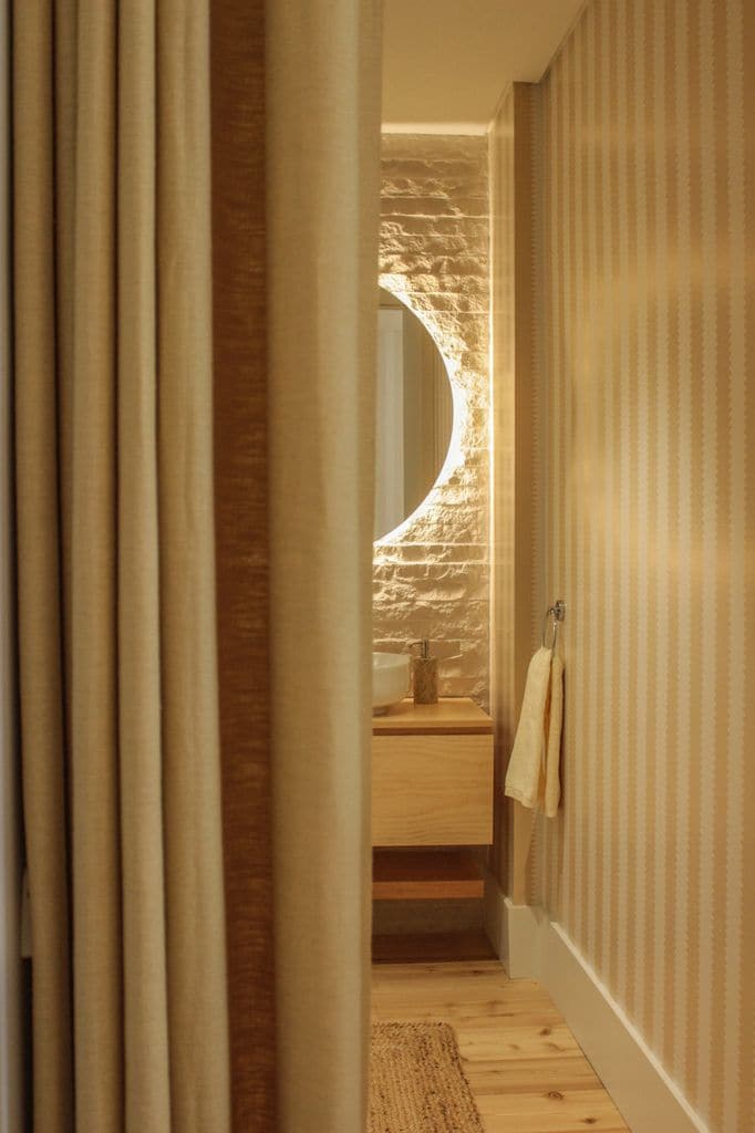 Baño con mueble de madera y espejo redondo