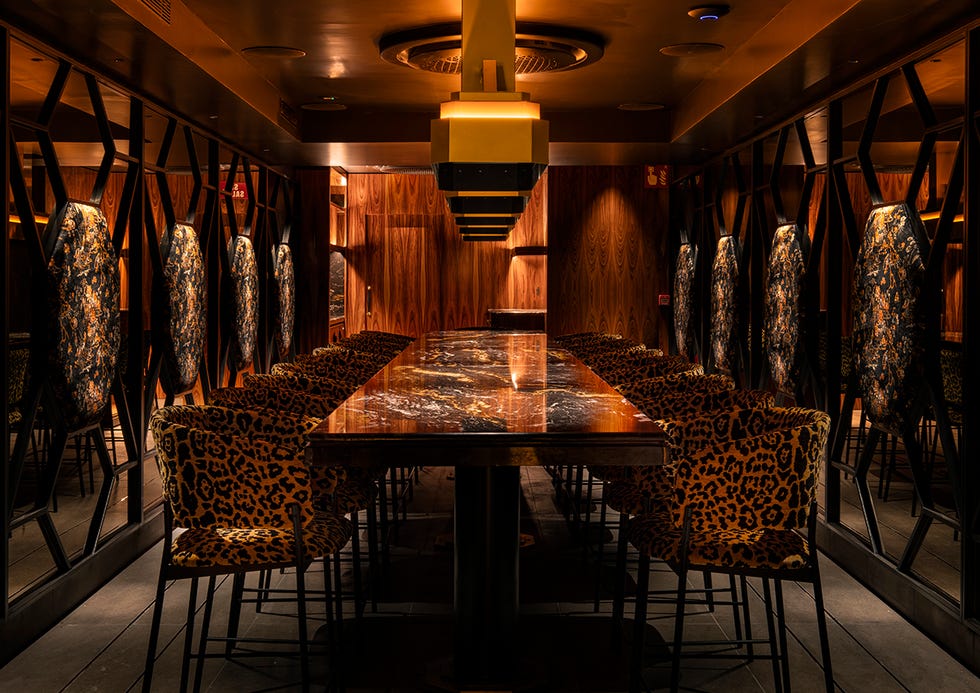 aitaren restaurante, salon oscuro con mesa extralarga, paredes de espejo y sillas animal print