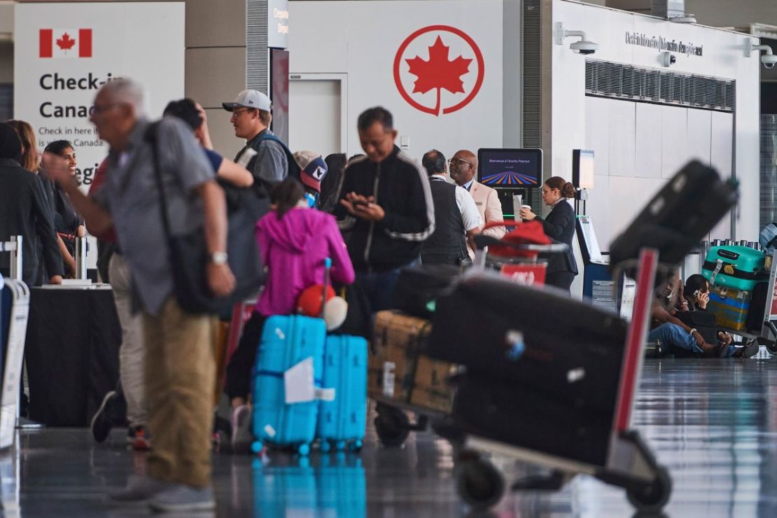Los viajeros esperan fuera de las puertas de embarque de Air Canada mientras los auxiliares de vuelo protestan en el Aeropuerto Internacional Pearson de Toronto el 16 de agosto de 2025.