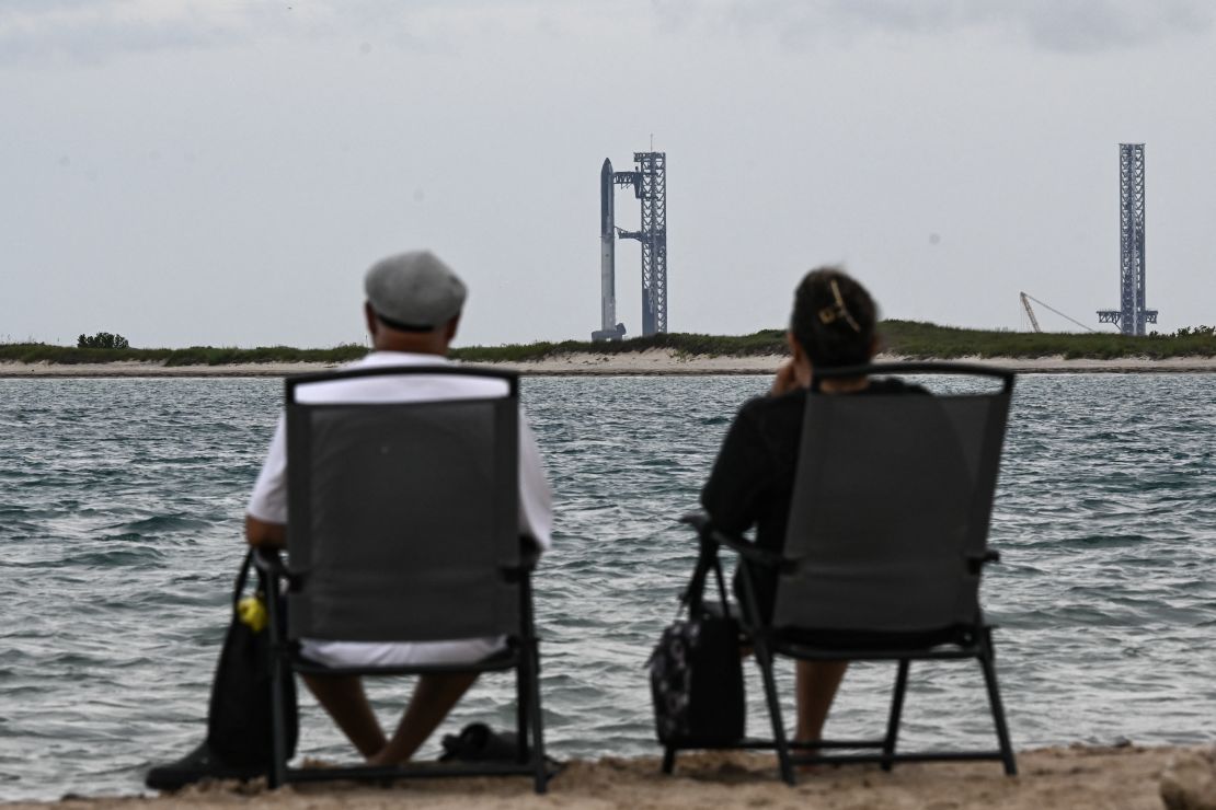 Personas observan el cohete Starship de SpaceX en Starbase, Texas, visto desde South Padre Island el 25 de agosto de 2025.