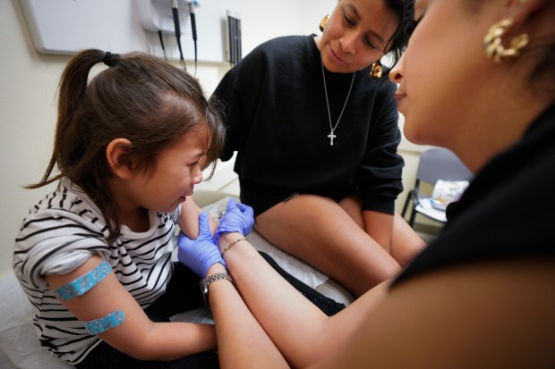 At Logan Heights Family Health Center on Saturday, May 31, 2025, in San Diego, Kenia Sandoval (c) of Lemon Grove sat with her daughter, Jade Sandoval while she is given the Measles, Mumps and Rubella (MMR) vaccine. Health officials at Logan Heights Family Health Center on Saturday, May 31, 2025, in San Diego, are prepared to vaccinate up to 300 children with the measles, mumps, and rubella (MMR) vaccine. . (Nelvin C. Cepeda / The San Diego Union-Tribune)