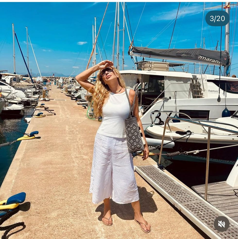 woman in white outfit on a marina walkway surrounded by boats