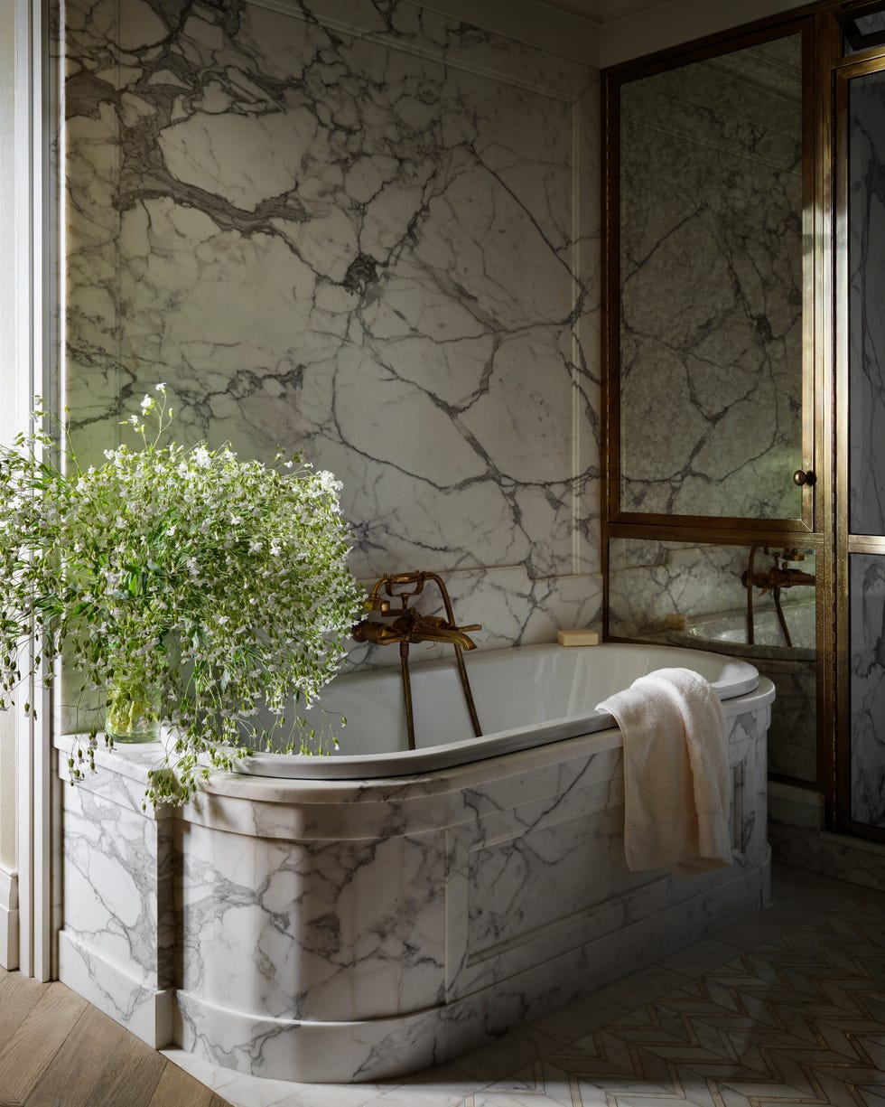 Luxurious marble bathroom featuring a vintage tub and floral arrangement.