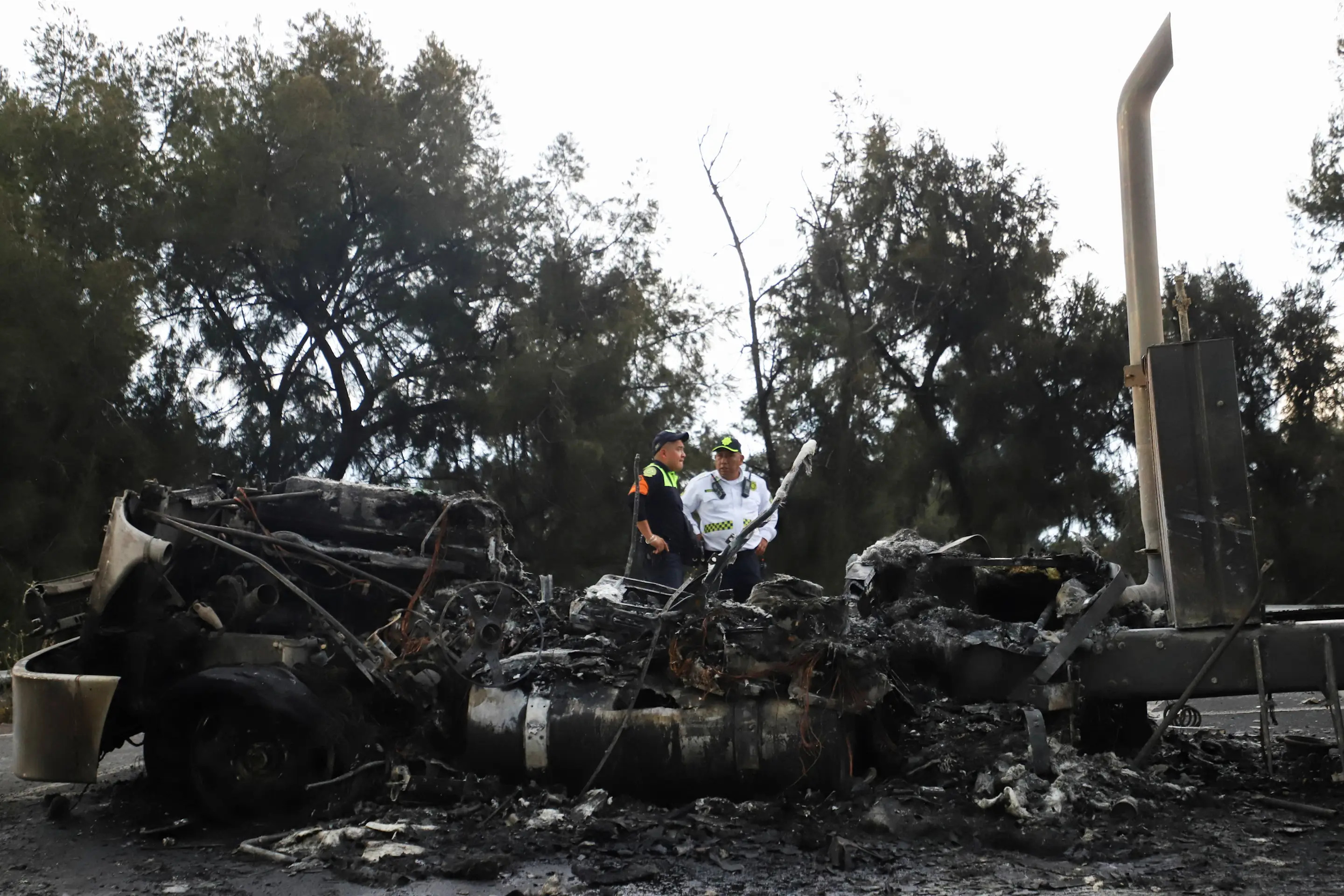 Police officers stand next to the charred remains of a trailer, one of the vehicles damaged in a gas tanker explosion on Ignacio Zaragoza Avenue, where multiple individuals sustained burn injuries after the tanker overturned, in Mexico City, Mexico, September 10, 2025. REUTERS/Quetzalli Blanco