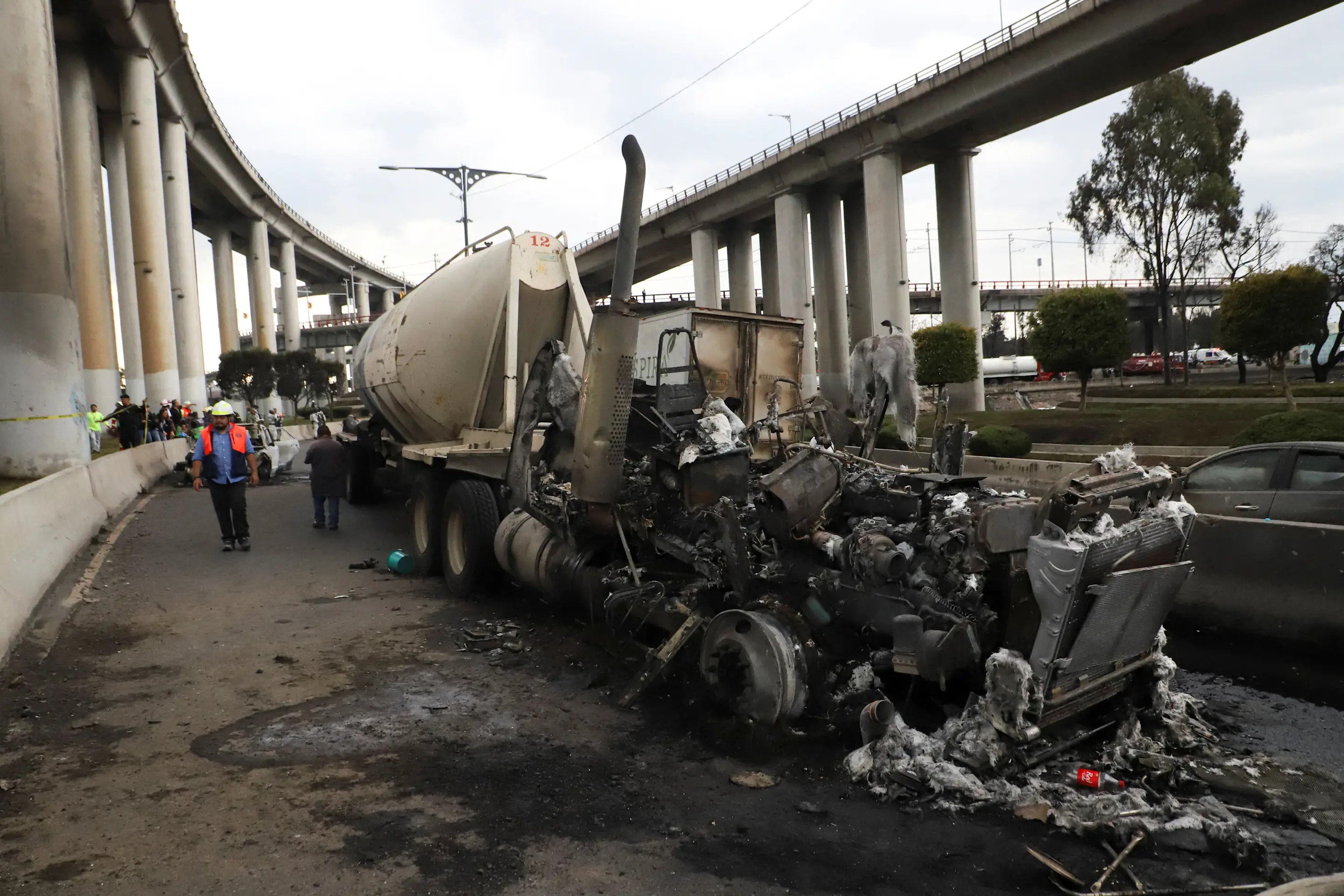 A man walks nex to the charred remains of a trailer, one of the vehicles damaged in a gas tanker explosion on Ignacio Zaragoza Avenue, where multiple individuals sustained burn injuries after the tanker overturned, in Mexico City, Mexico, September 10, 2025. REUTERS/Quetzalli Blanco