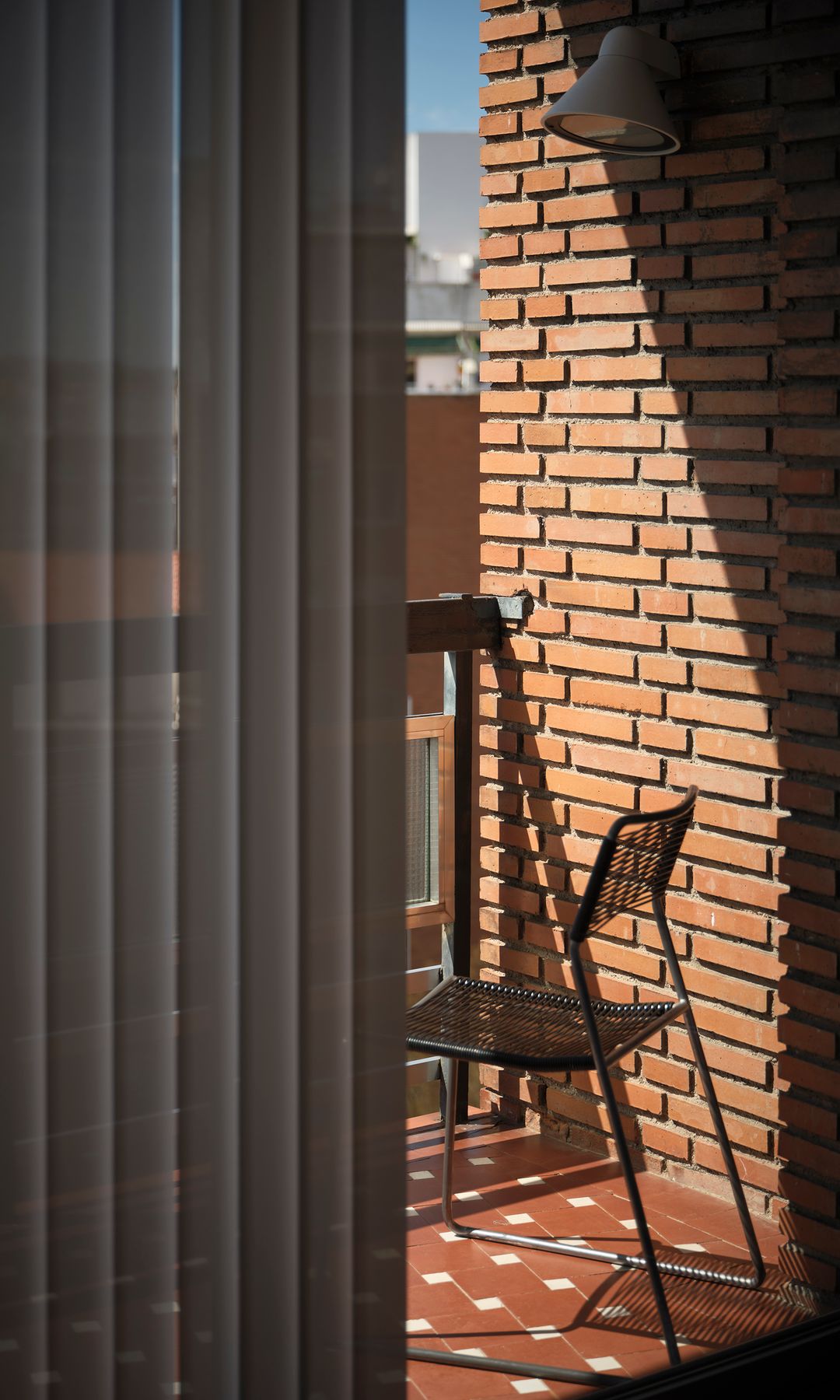 Terraza con pared de ladrillo, suelo de baldosas, silla