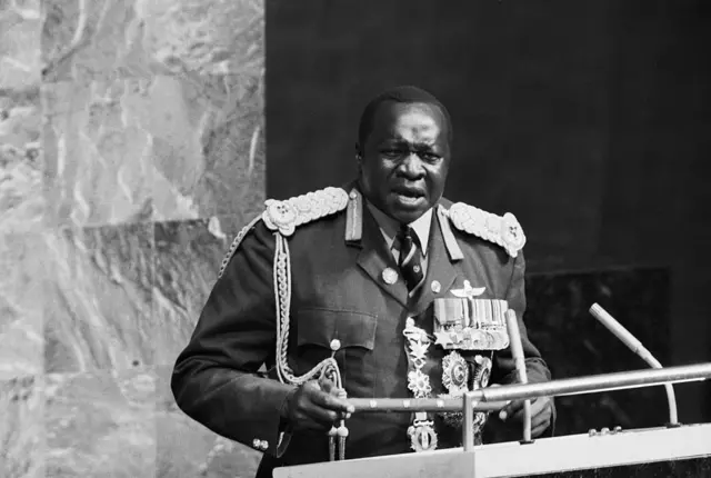 Imagen en blanco y negro del presidente de Uganda Idi Amin, quien viste un  uniforme militar de mariscal de campo con muchas condecoraciones mientras habla desde el podio de la Asamblea General de la ONU.