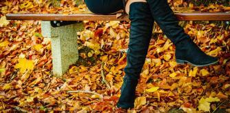 Una mujer sentada en un banco con botas altas negras