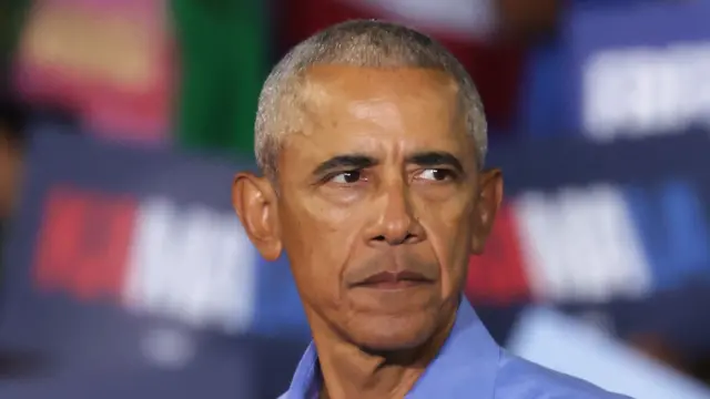Obama mira a su izquierda vestido con camisa azul. 
