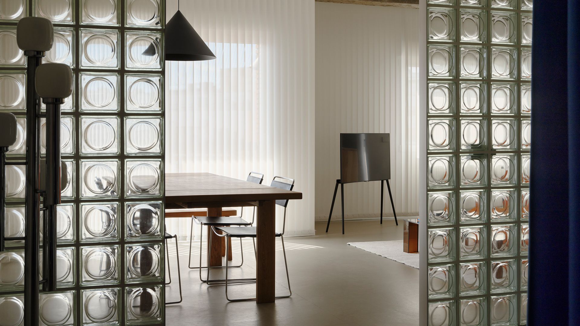 Entrada al comedor con tabique de payés, mesa de comedor de madera, lámpara negra y sillas de comedor metálicas y negras