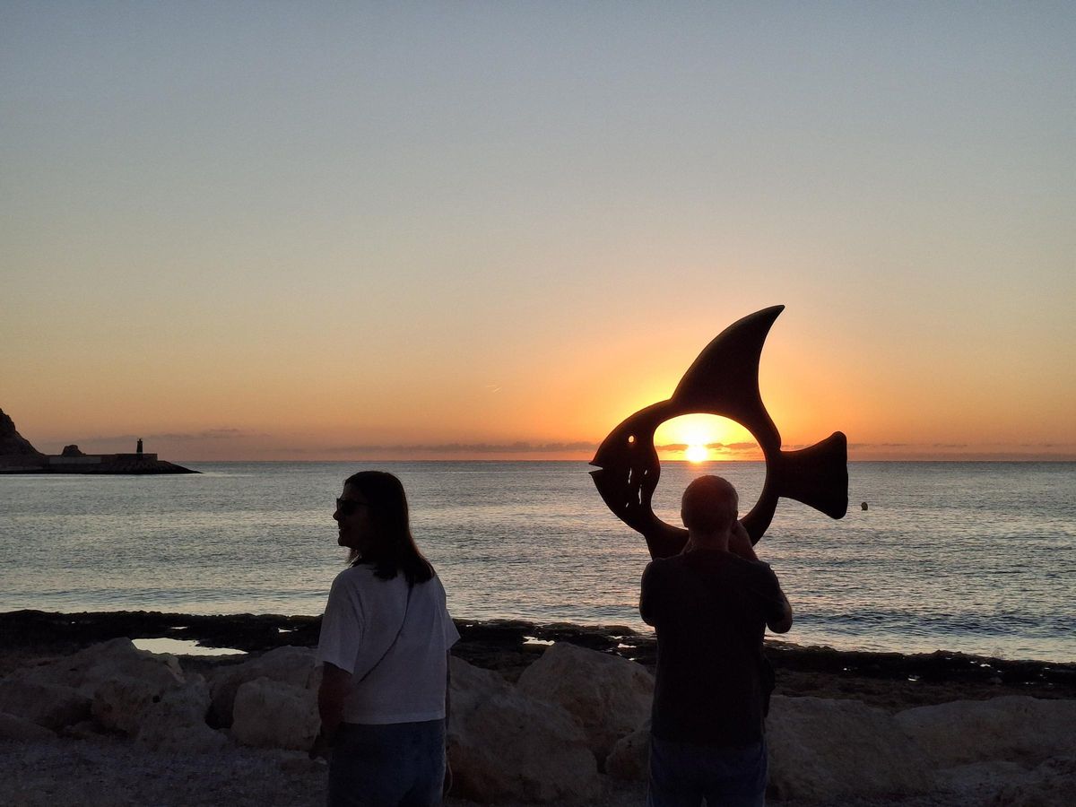 Un madrugador toma con el móvil la foto del sol en la panza de la escultura