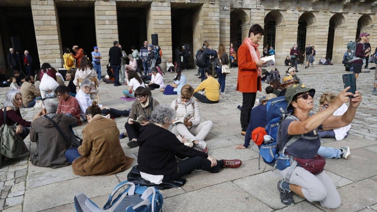 Una peregrina se hace un selfie junto la varias personas en plena lectura coral.