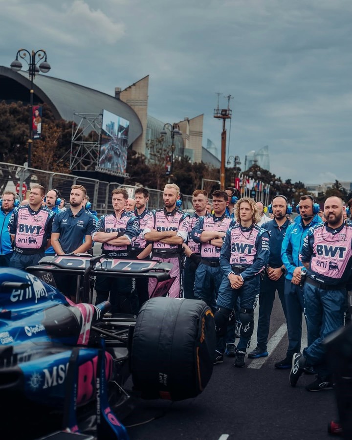 Todo el equipo unido alrededor del coche con el traje rosa. (@alpinef1team)