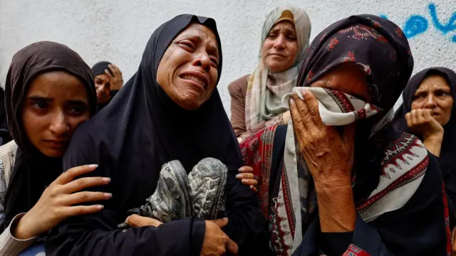 Fotografía de archivo que muestra a la madre del adolescente palestino Khaled al-Shinbari sosteniendo sus zapatos durante su funeral en el hospital al-Shifa, en la ciudad de Gaza (28 de agosto de 2025).