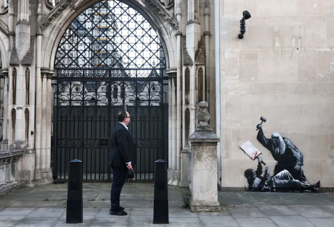 Una persona mira un nuevo mural del artista anónimo Banksy en los Tribunales Reales de Justicia de Londres, el 9 de septiembre de 2025.