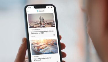 Una persona sujeta un móvil con artículos de CaixaBank