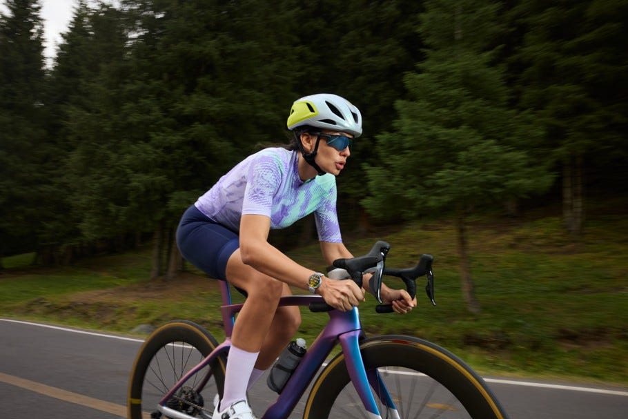 person cycling on a road surrounded by trees