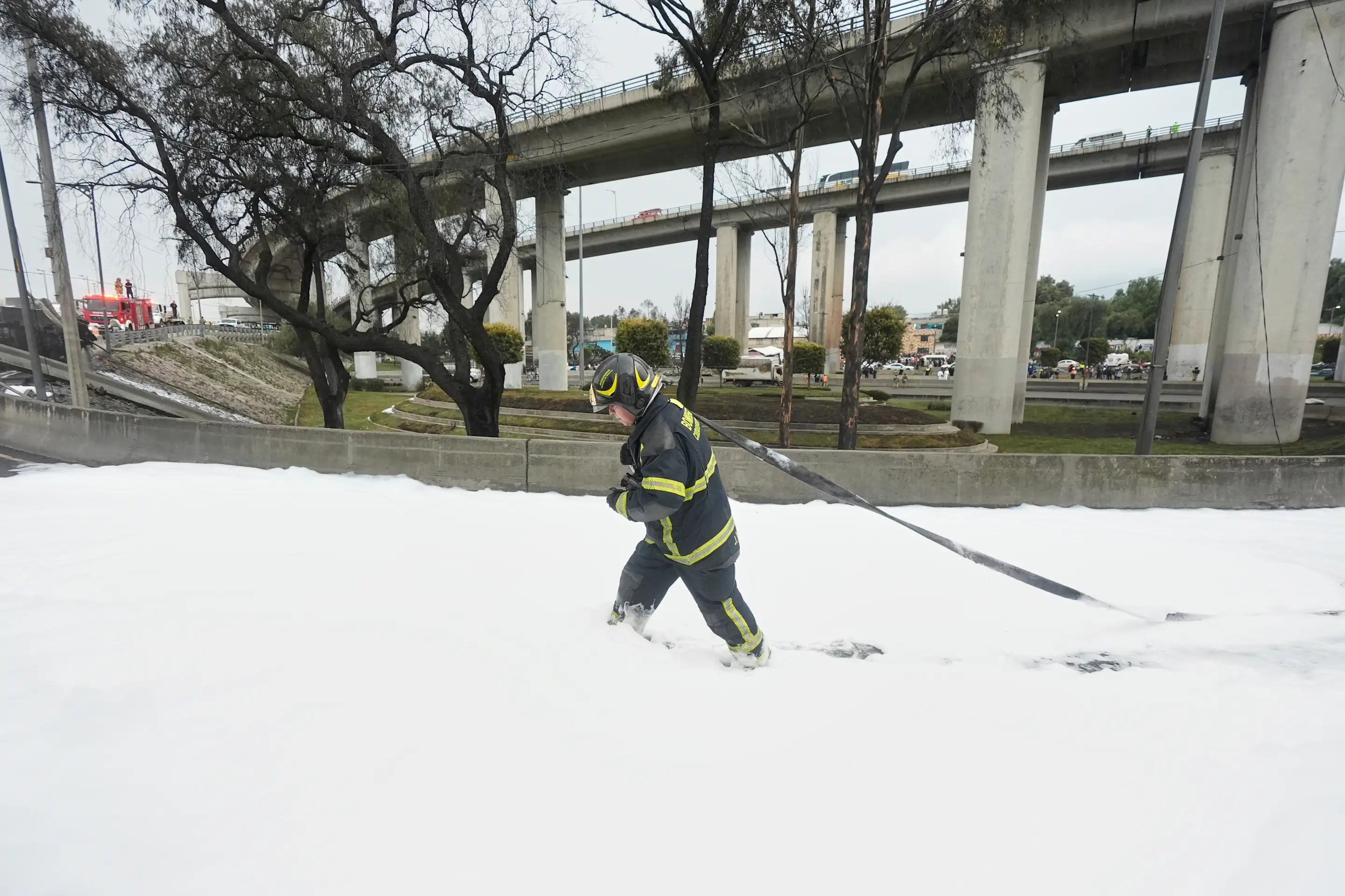 A firefighter walks through foam next to extinguish a gas tanker, not pictured, that exploded under a highway underpass, in Mexico City, Wednesday, Sept. 10, 2025. (AP Photo/Fernando Llano)