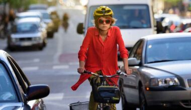 Ciclista con casco circulando en ciudad entre coches con riesgo de dooring al abrirse una puerta inesperadamente