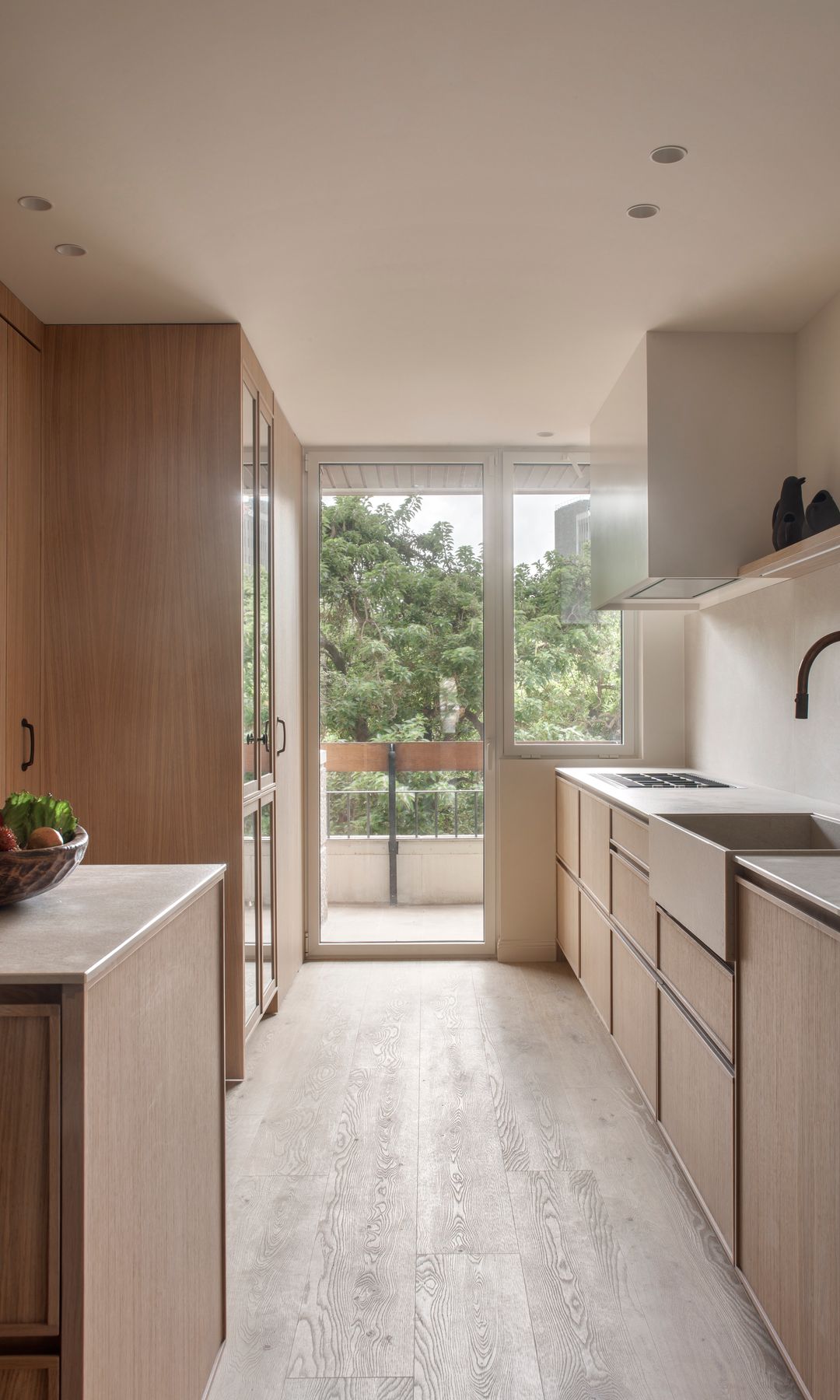 Cocina madera en paralelo con suelo de madera, salida a la terraza, balda blanca y campana de acero