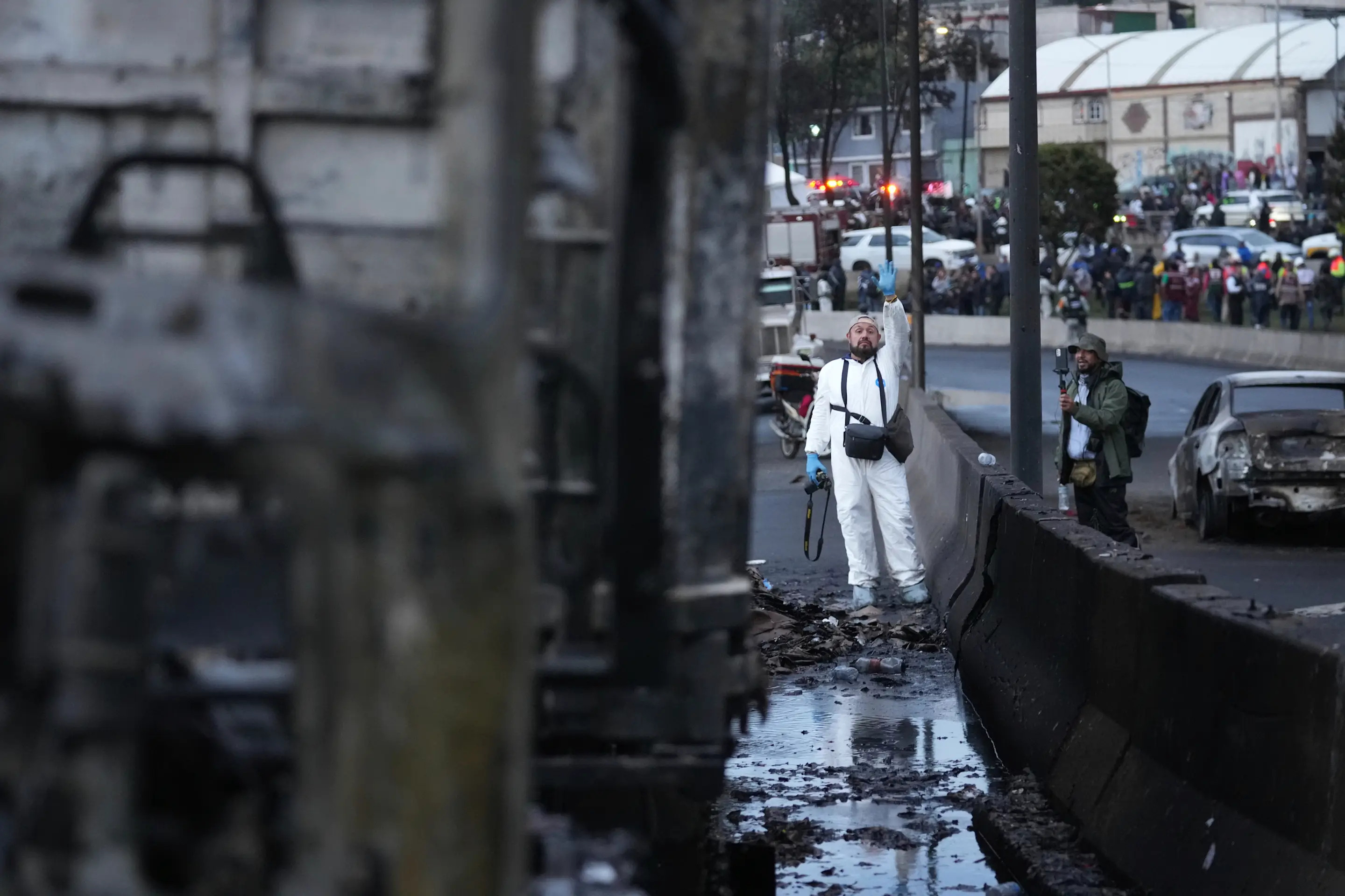 A forensic worker waves next to a damaged truck after a gas tanker exploded under a highway overpass in Mexico City, Wednesday, Sept. 10, 2025. (AP Photo/Fernando Llano)