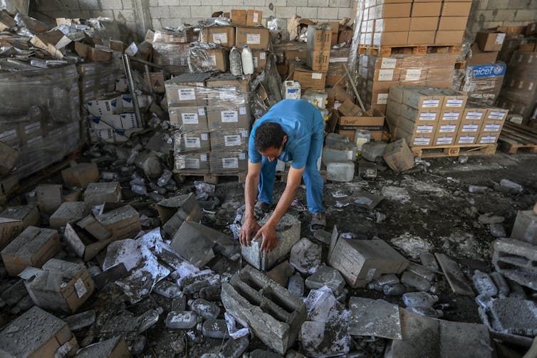 Un trabajador palestino de un hospital inspecciona los daños causados por un bombardeo en un almacén.