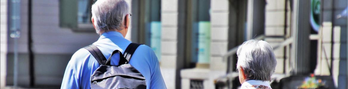 Dos personas mayores con mochilas hacen turismo en una ciudad
