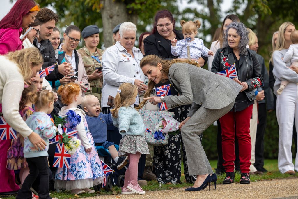 Kate Middleton con una niña durante un acto
