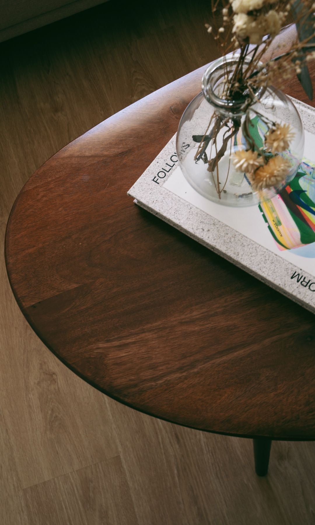 Mesa de centro de madera, con jarrón de cristal con flores secas y libros 