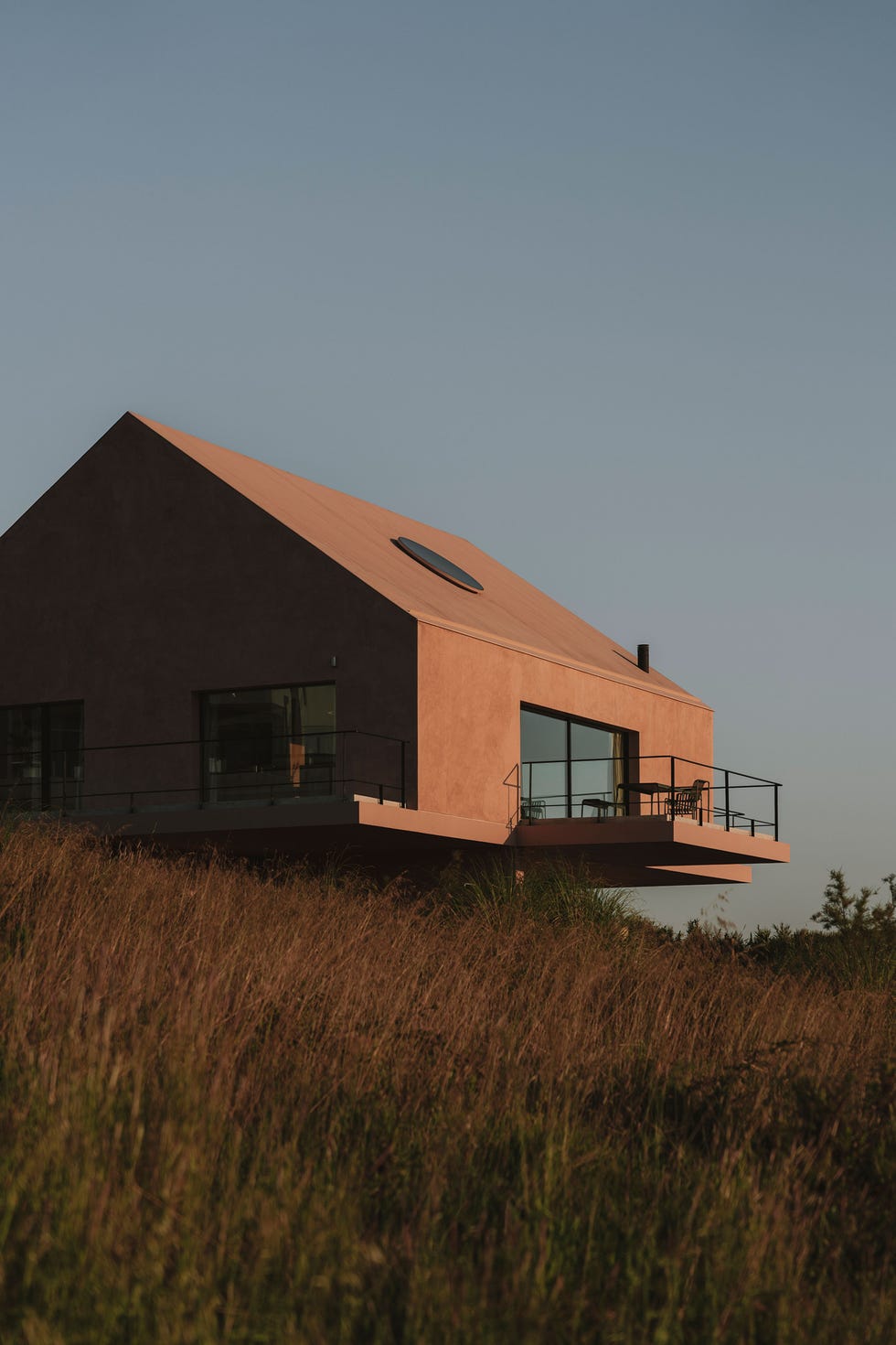 casa de vacaciones una sola planta flota sobre el terreno, tiene un tejado a dos aguas y oculos disenados con un modelo en 3d