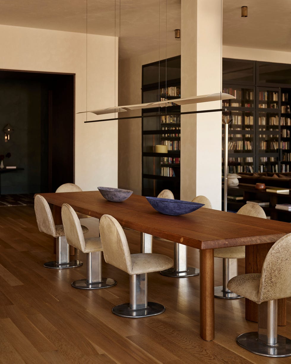 Modern dining area featuring a long wooden table and upholstered chairs.
