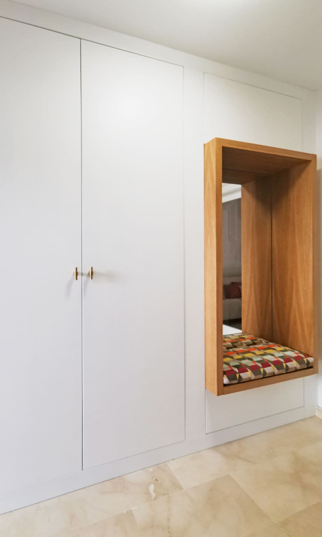 Recibidor con estructura a medida que cuenta con armario con puertas blancas, banco y espejo