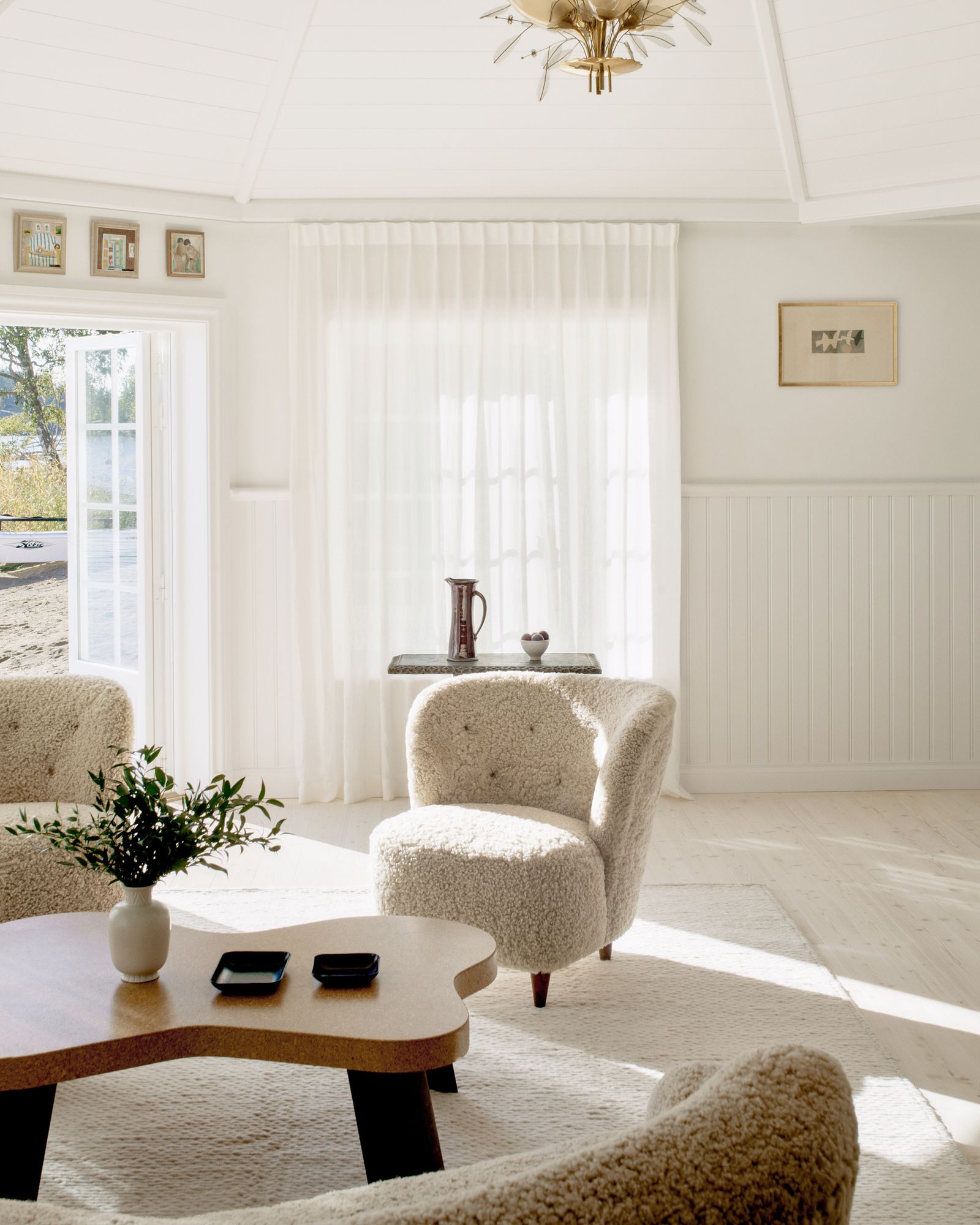 sala con butacas blancos mesa de centro de madera paredes con paneles blancos.
