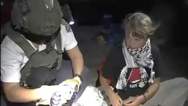 Greta Thunberg, junto a un efectivo israelí, que lleva casco y chaleco balístico. 