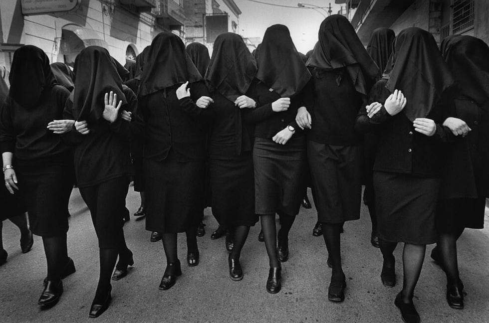 group of women in black clothing with covered faces marching together