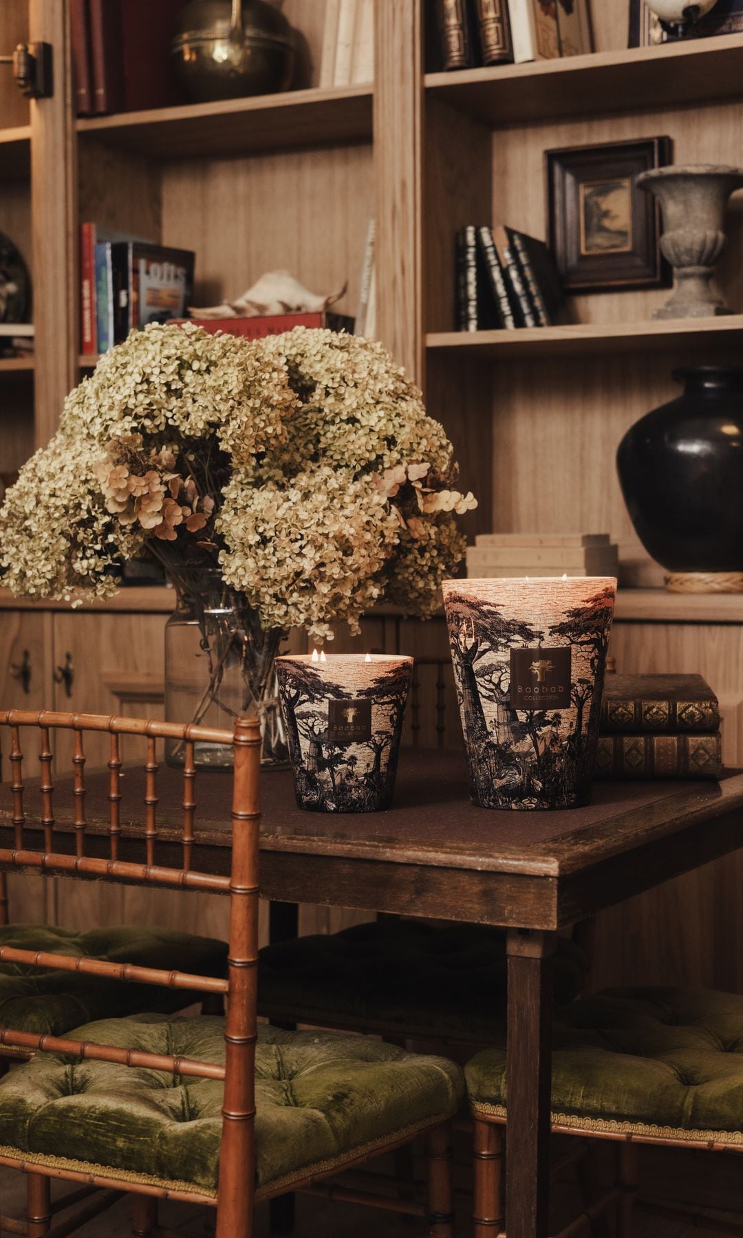 Mesa de comedor de madera con ramo de hortensias, velas y sillas de madera con cojín de terciopelo verde