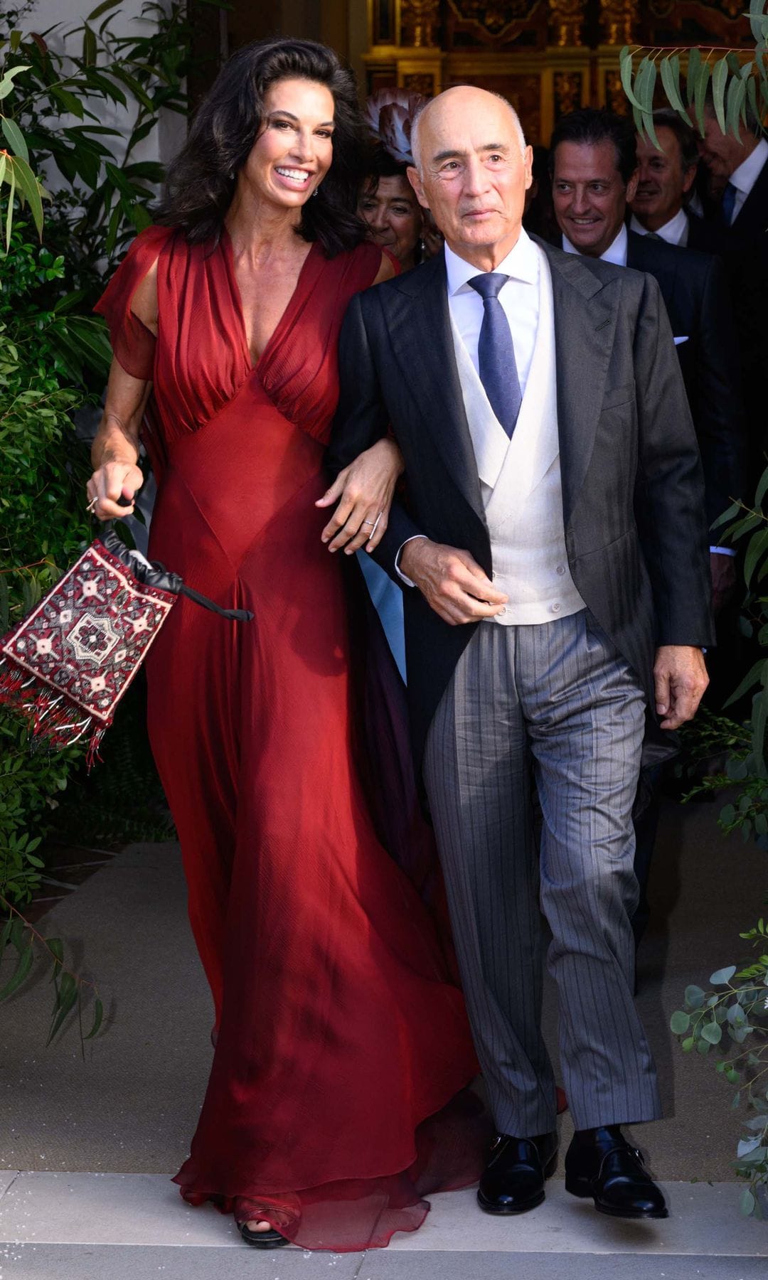 La madre de la novia, Gaella de la Serna, con un vestido largo de seda color cereza, sale de la iglesia del brazo de Rafael del Pino, padre del novio, tras la ceremonia religiosa, que tuvo lugar en la parroquia de Santa Ana de Manilva