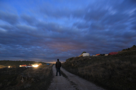 El caminante solitario ante la promesa de la luz y el refugio. La noche ha llegado, y el pueblo lo espera.