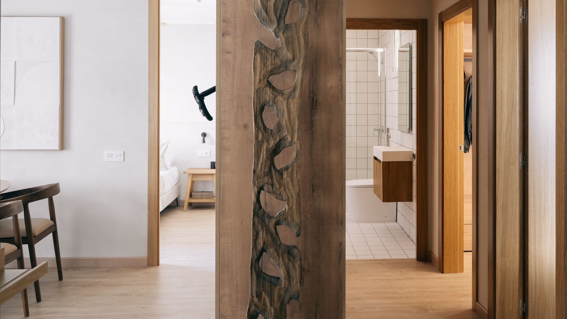 Entrada piso con vista del baño, del comedor y viga de madera vista, puertas de madera