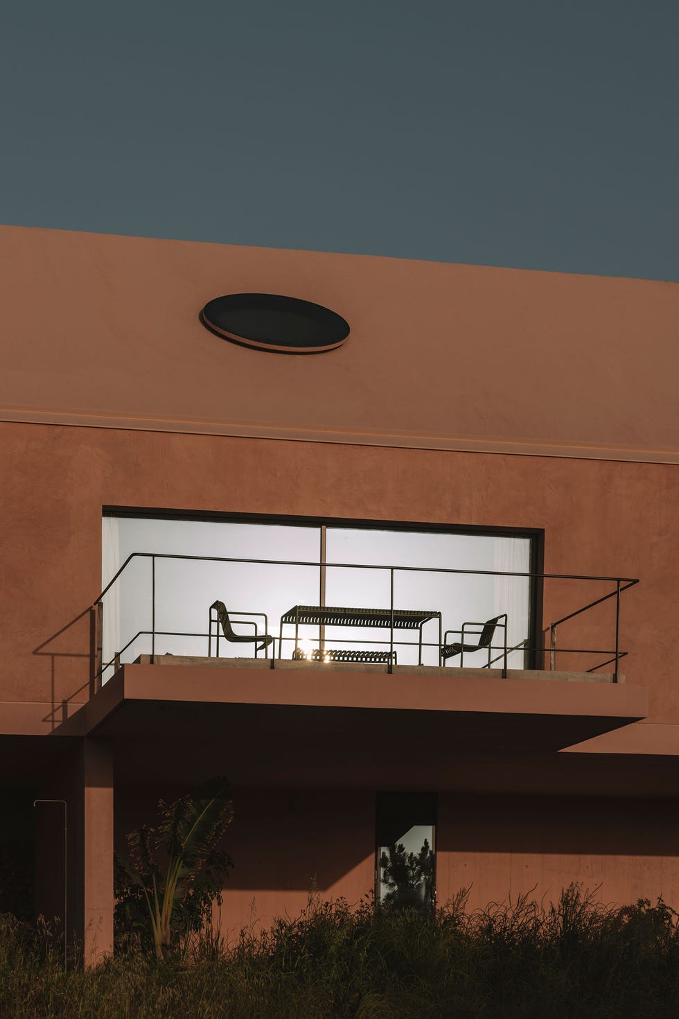 casa de vacaciones una sola planta flota sobre el terreno, tiene un tejado a dos aguas y oculos disenados con un modelo en 3d