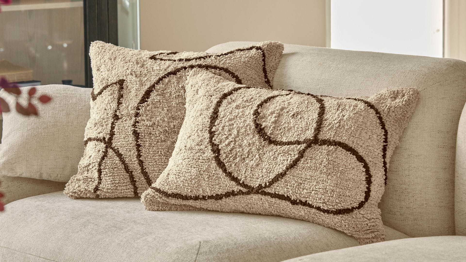 Sofá beige con cojines en beige y motivos marrones