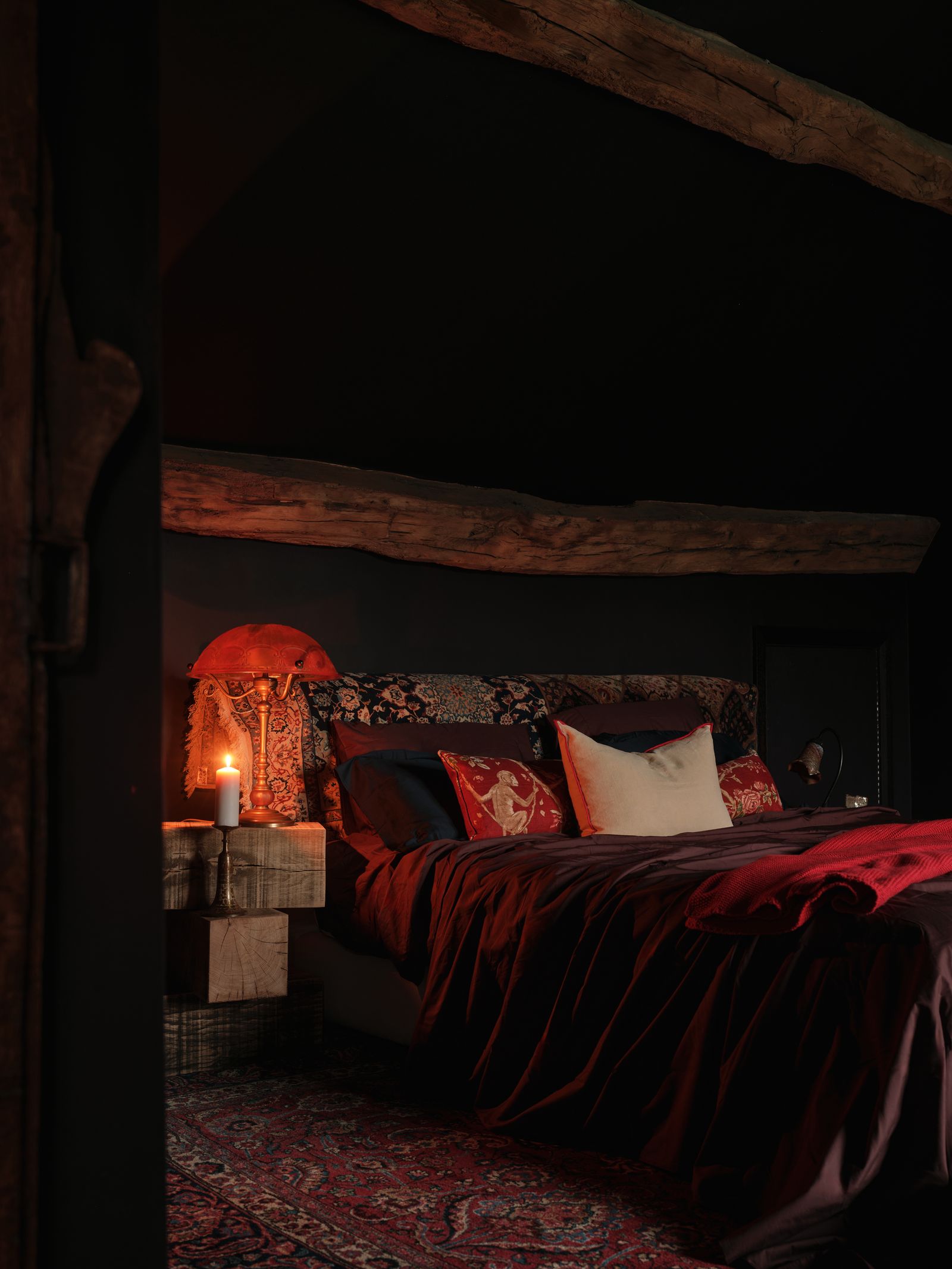 Dormitorio de casa de campo antigua con vela en la mesilla