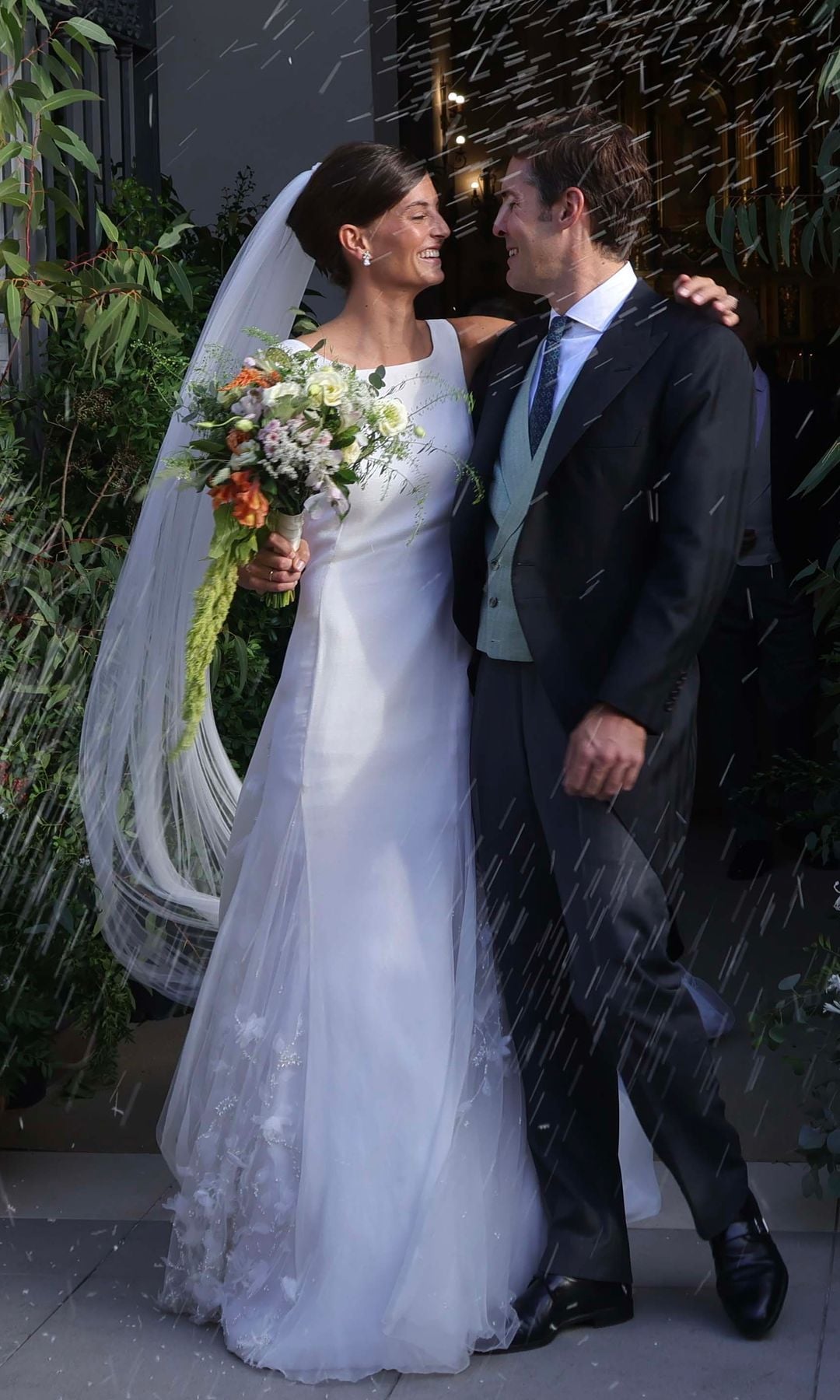 Victoria y Rafael, ya convertidos en marido y mujer, reciben muy sonrientes una lluvia de arroz a las puertas del templo