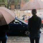 Personas con paraguas bajo la lluvia en una calle de Baleares