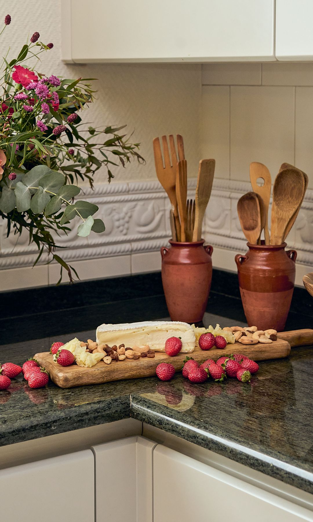 Una tabla de quesos con frutos secos y fresas