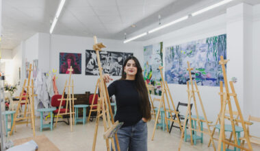 Joven pintora en su estudio rodeada de caballetes y obras de arte