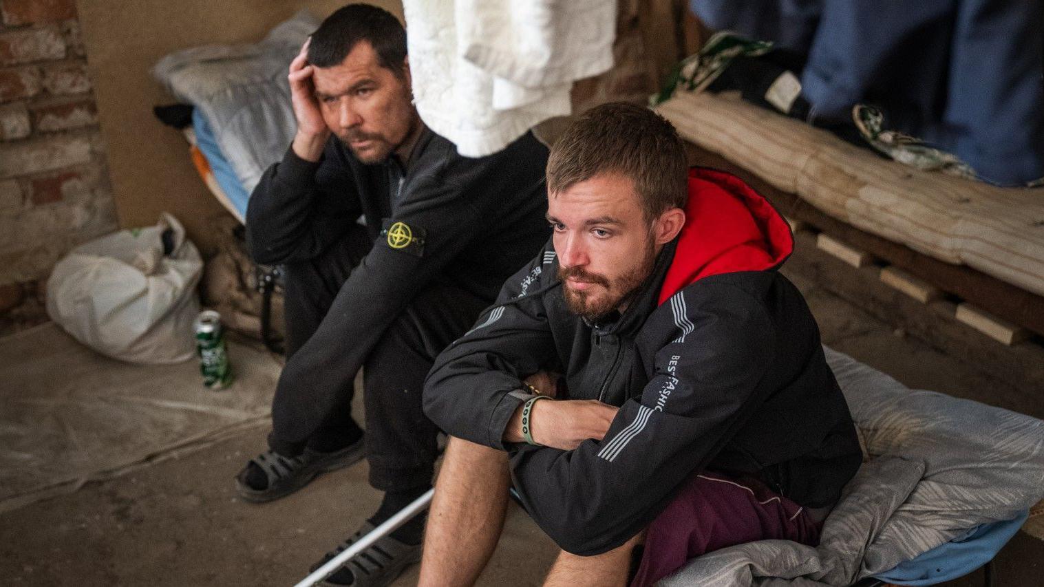 Dos soldados convictos exhaustos se recuperan en un cuartel del sur de Ucrania tras una temporada en el frente.