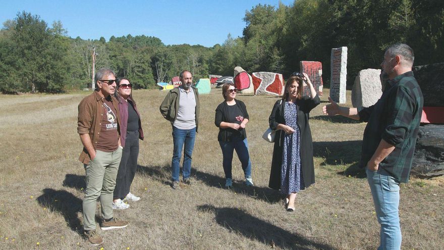 Javier Varela, a la derecha de la imagen, explica sus trabajos de repintado ante las obras en O Rexo.