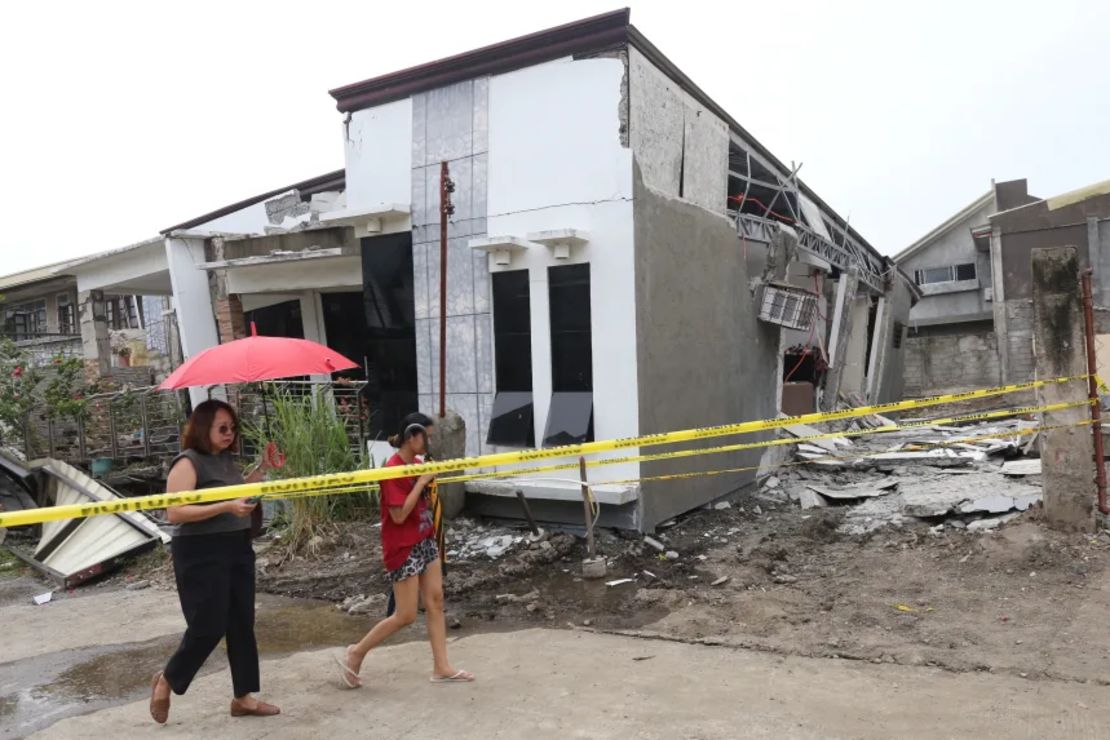 Dos mujeres caminan junto a una casa dañada después de un fuerte sismo en la ciudad de Davao, en el sur de Filipinas, el 10 de octubre.
