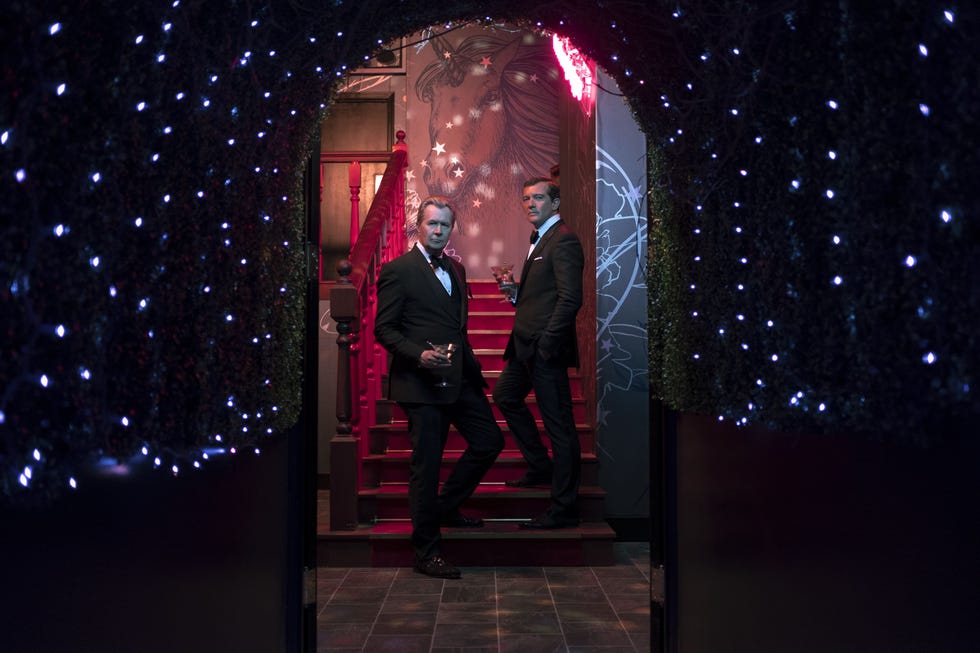 two men in formal attire at a stylish venue with decorative lighting